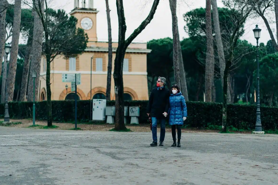 couple standing on gray concrete pavement near brown concrete building during daytime