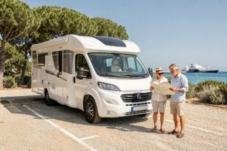 Camping-car blanc garé dans un parking près de l'embarcadère de Porquerolles avec un couple consultant une carte