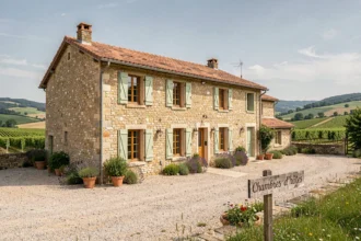 Façade d'une chambre d'hôtes typique dans l'Ain, maison en pierre avec volets verts et jardin fleuri