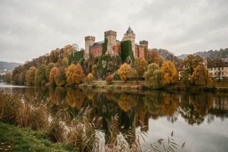 Vue panoramique du château de Heidelberg en automne reflété dans le Neckar avec les ruines en grès rouge entourées de feuillages dorés