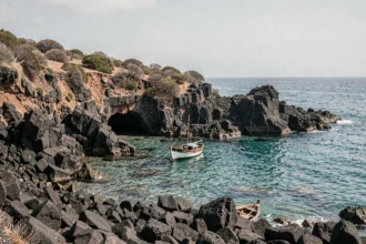 Côte volcanique des îles Éoliennes avec rochers basaltiques noirs et eau turquoise cristalline