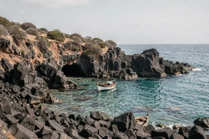 Côte volcanique des îles Éoliennes avec rochers basaltiques noirs et eau turquoise cristalline